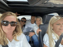 a group of people are posing for a picture in the back of a car