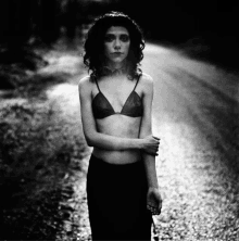 a woman in a bra stands on a road