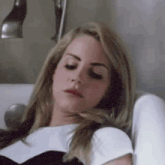 a woman is laying on a bed with her eyes closed and her head resting on her arm .