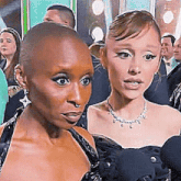 two women are standing next to each other in front of a crowd of people .