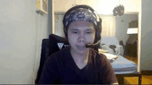 a man wearing headphones and a bandana looks at the camera in a living room