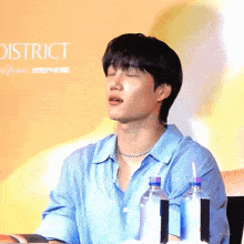 a man in a blue shirt sitting in front of a sign that says district
