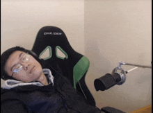 a man wearing glasses and headphones is laying down in a dxr racer chair