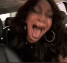 a woman is sticking her tongue out while sitting in the back seat of a car