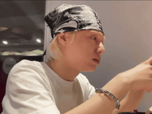 a man wearing a bandana and a bracelet looks at something