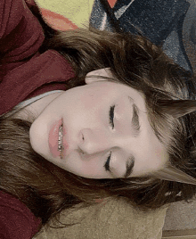 a girl with braces on her teeth laying on a blanket