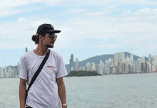 a man wearing a crewmacs shirt stands in front of a city skyline