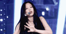 a woman with long black hair is singing into a microphone on a stage