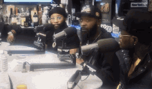 three men are sitting at a table with microphones in front of them and a new york times sign in the background