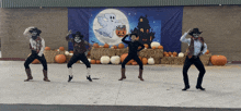 a group of people in cowboy costumes are dancing in front of a halloween sign