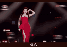 a woman in a red dress stands on a stage with chinese writing on the bottom