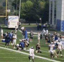 a group of football players on a field with a blue truck in the background that says ' blumac '