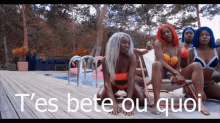 a group of women in bikinis are sitting on a deck near a pool with the words t'es bete ou quoi on the bottom