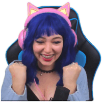 a woman with blue hair and cat ears is sitting in a chair with her fists in the air