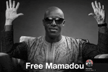 a black and white photo of a man with his hands in the air and the words free mamadou below him