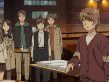 a group of people standing around a table with a man in a red cardigan