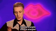 a man is talking about positive energies in front of a pink lips .