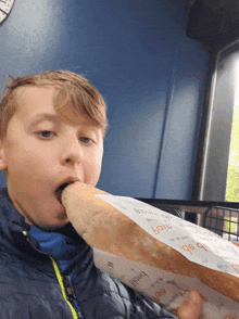 a young boy is eating a baguette that has the word bnbl on it