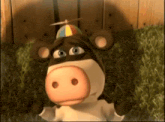 a cartoon cow wearing a colorful hat is laying on the grass