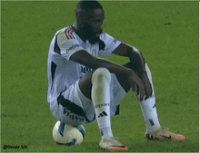 a soccer player is kneeling down on the field with a soccer ball