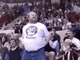 a man in a white shirt with a lion on it is jumping in the air in front of a crowd .