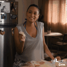 a woman in a bikini is smiling while holding a piece of bread in front of a refrigerator that says showtime on it