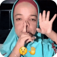 a woman in a hijab is making a shhh gesture with her hand .