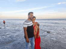 a man and woman pose for a picture on a beach