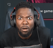 a man wearing headphones looks surprised in front of a screen that says w games