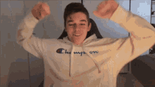 a young man wearing a white champion hoodie is flexing his muscles