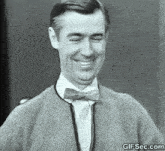 a black and white photo of a man wearing a bow tie and sweater