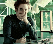 a man covering his face with his hands while sitting at a table
