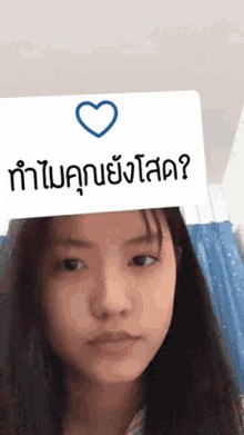 a girl is wearing a filter that says " ทํา ไม คุณ ยัง โสด " on her head