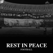 a black and white photo of a stadium with a banner that says created by the poor stolen by the rich rest in peace football