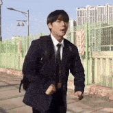 a man wearing a suit and tie is walking down a street