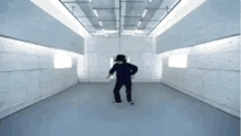 a man in a hat is dancing in a hallway