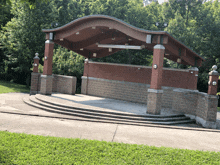 a stage with brick pillars and a wooden roof in a park