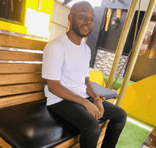 a man wearing a white shirt is sitting on a wooden bench