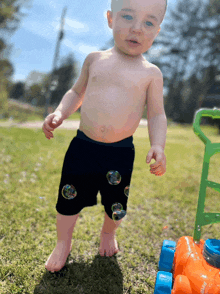 a shirtless baby is playing with soap bubbles