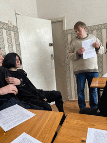 a man is holding a piece of paper in front of a group of students