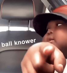 a person sitting in a car with the word ball knower written on the back seat