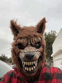 a man wearing a werewolf mask and a plaid shirt is taking a selfie .