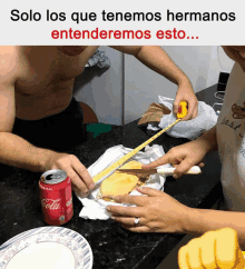 a man and woman measuring a sandwich with a can of coca cola in the foreground