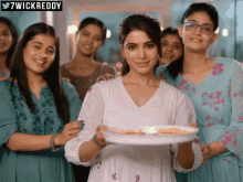 a woman in a white dress holds a plate of food in front of a group of women with the hashtag 7wickreddy