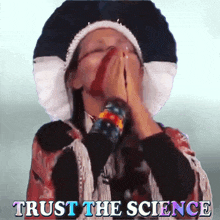 a woman covering her face with her hands with the words trust the science written below her