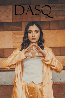 a woman making a heart shape with her hands in front of a dasq sign