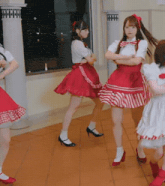 a group of girls in red and white dresses are standing on a tiled floor