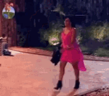 a woman in a pink dress is walking down a sidewalk