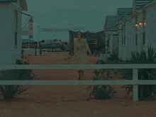 a woman in a yellow dress stands on a white fence in front of a sign that says ' trucks baton '