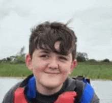 a young boy is wearing a life jacket and smiling while sitting on a boat .